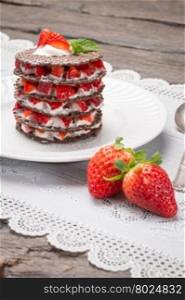 Strawberries desert with cream and wafer served on plate over table top.