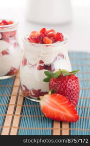 Strawberries desert with cream served on glass cups over table top.