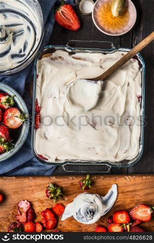 Strawberries dessert or cake with yogurt cream, cooking preparation on rustic kitchen table , top view