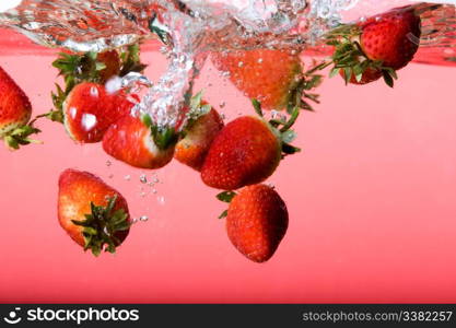 Strawberries falling in red water with splash and bubbles