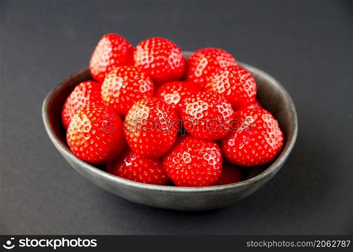 Strawberries in a bowl. Black background. Studio shooting. Strawberries in a bowl. Black background