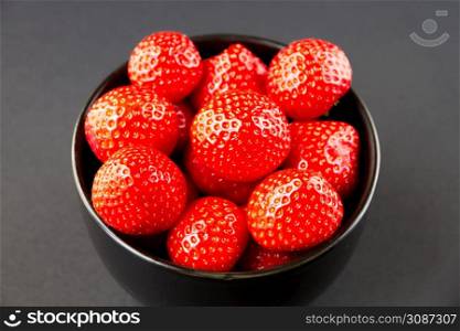 Strawberries in a bowl. Black background. Studio shooting. Strawberries in a bowl. Black background