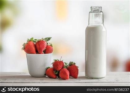 Strawberries in a cup with a bottle of milk