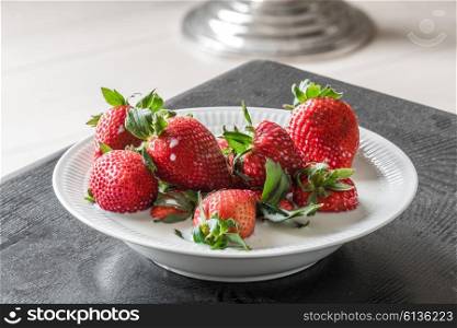 Strawberries in a porcelain bowl on a black table