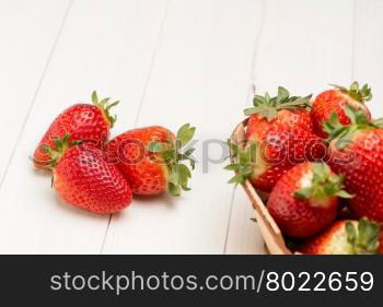Strawberries in a small basket on wooden table.