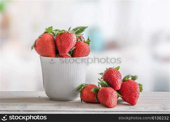 Strawberries in a white bowl on a wooden table