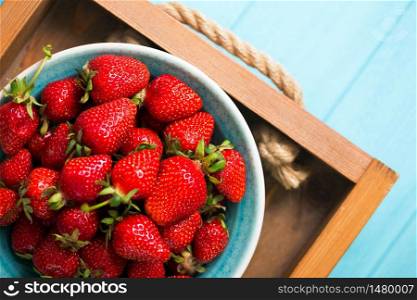 Strawberries in bowl on a blue wooden table