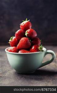Strawberries in cup on rustic background