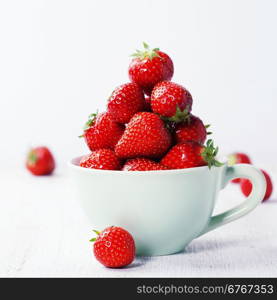 Strawberries in cup on rustic background