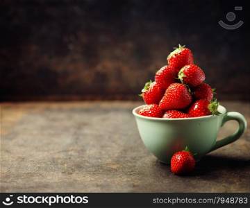 Strawberries in cup on rustic background