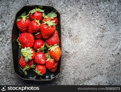 Strawberries in paper box on gray concrete background, top view. Superfood concept