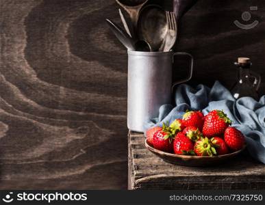 Strawberries in plate on dark rustic kitchen table background, still life