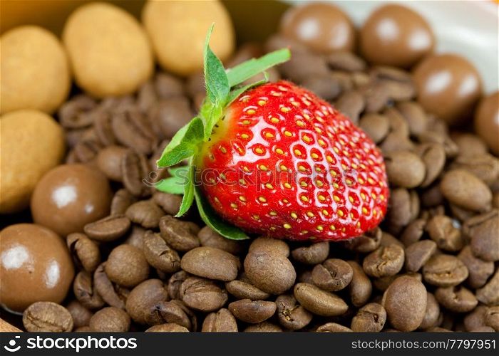 strawberries lying on a background of coffee beans, cinnamon and the sweets