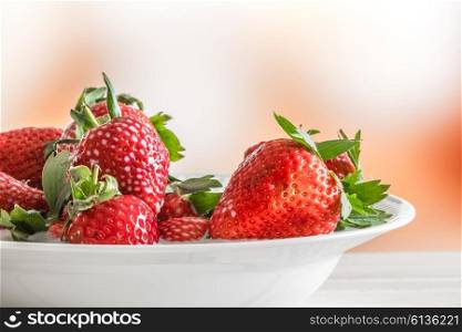 Strawberries on a white plate at a table