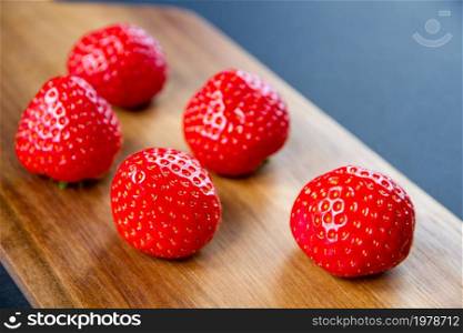 Strawberries on a wooden cutting board. Black background. Strawberries on a cutting board. Black background