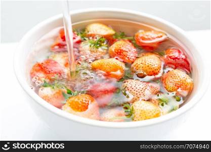 Strawberries soaked in water. Washing fresh fruit on white background.