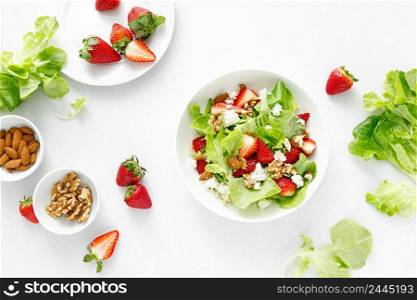 Strawberry and cottage cheese fresh fruit salad with walnut, almond and lettuce, top down view, flat lay