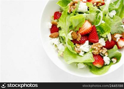 Strawberry and cottage cheese fresh fruit salad with walnut, almond and lettuce, top down view, flat lay