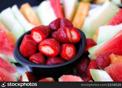 Strawberry And Melon Slices. A bowl of cleaned strawberries surrounded by slices of watermelon cantaloupe and honeydew melon