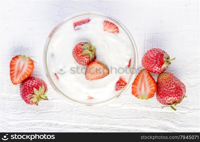 strawberry and yogurt in a wooden bowl on white wooden background