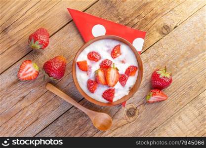 strawberry and yogurt in a wooden bowl on wooden background