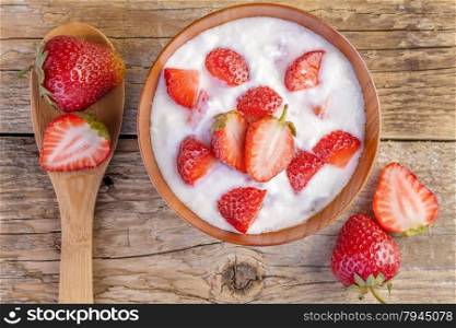 strawberry and yogurt in a wooden bowl on wooden background