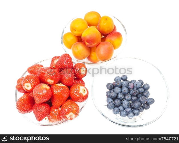 Strawberry, apricot and blueberries in glass bowls towards bright background