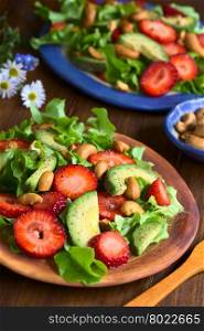 Strawberry, avocado, lettuce salad with cashew nuts on plate, photographed on dark wood with natural light (Selective Focus, Focus in the middle of the first salad)