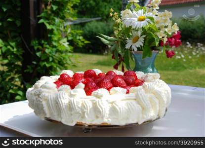 Strawberry cake and flowers at a table in a garden