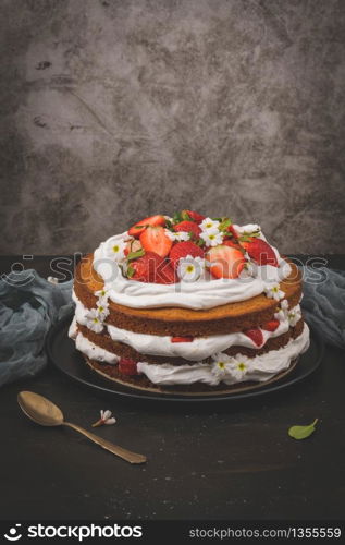 Strawberry cake, strawberry sponge cake with fresh strawberries and sour cream on a dark kitchen countertop.