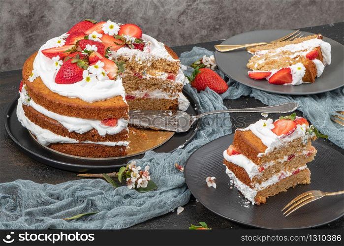 Strawberry cake, strawberry sponge cake with fresh strawberries and sour cream on a dark background