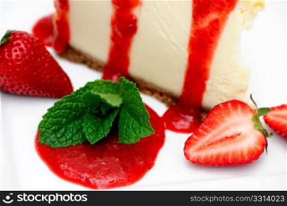 Strawberry Cheesecake. Slice of cheesecake with fresh strawberries and and a bright red strawberry sauce dripping over the sides on the dessert.