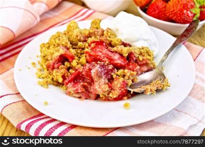 Strawberry crumble in a plate with a spoon on a napkin, strawberries in a bowl on a wooden boards background