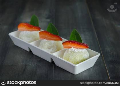 Strawberry Daifuku Mochi Japanese dessert on white plate over wooden background, still life