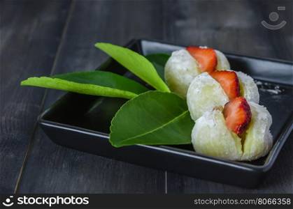 Strawberry Daifuku Mochi Japanese dessert . Strawberry Daifuku Mochi Japanese dessert on black dish over wooden background