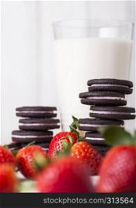 Strawberry dark cookies with glass of milk and fresh berries on wooden background
