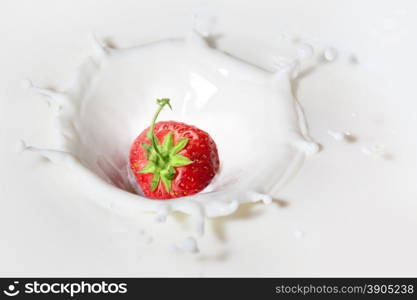 Strawberry dropped into milk with splash