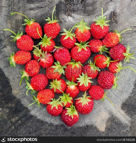 Strawberry Heart shape on old cracked stump, consept love strawberry summer, greeting card. Strawberry Heart shape on old cracked stump