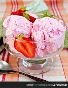 Strawberry ice cream in a glass bowl with strawberries, spoon on a napkin on a background of a linen tablecloth
