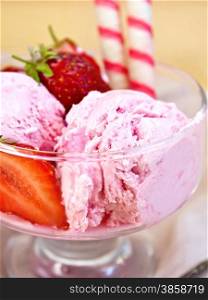 Strawberry ice cream in a glass bowl with wafer rolls and strawberries, napkin on a wooden boards background