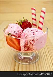 Strawberry ice cream in a glass bowl with wafer rolls and strawberries on a wooden boards background