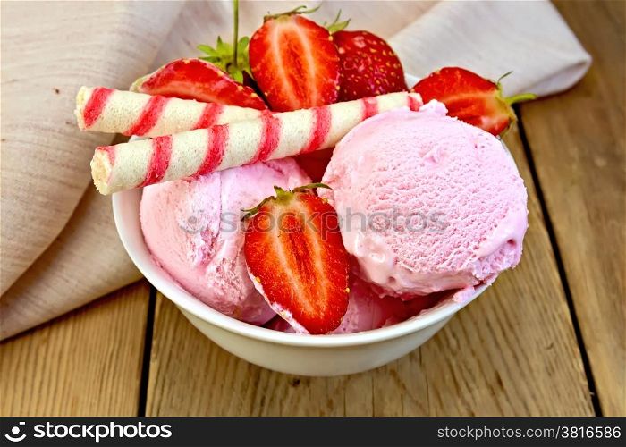 Strawberry ice cream in a white bowl with strawberries and wafer rolls, napkin on a wooden boards background