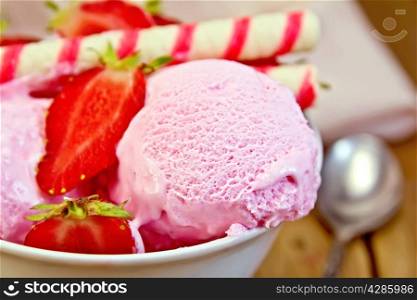 Strawberry ice cream in a white bowl with strawberries and wafer rolls, napkin on wooden board