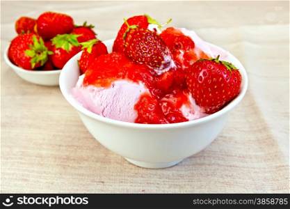 Strawberry ice cream in a white bowl with strawberries on a fabric background