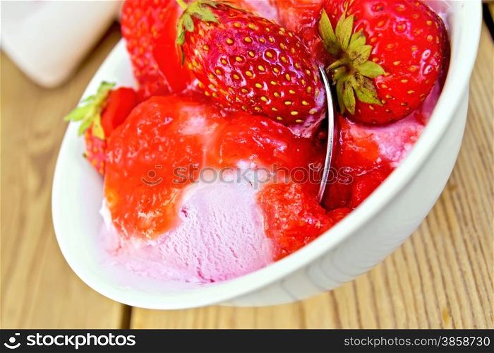 Strawberry ice cream in a white bowl with strawberries on a wooden boards background