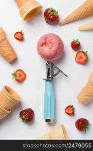 Strawberry ice cream scoop spoon with wafer cones and berries on white table flatlay