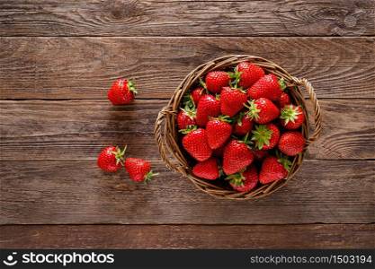 Strawberry in basket with twigs and leaves on rustic wooden table closeup