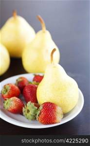 strawberry in plate and pear on a wooden table