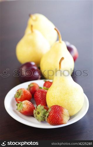 strawberry in plate,grapes and pear on a wooden table