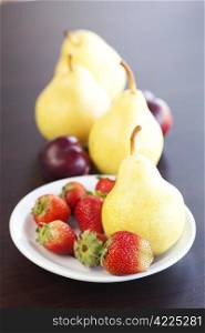 strawberry in plate,grapes and pear on a wooden table